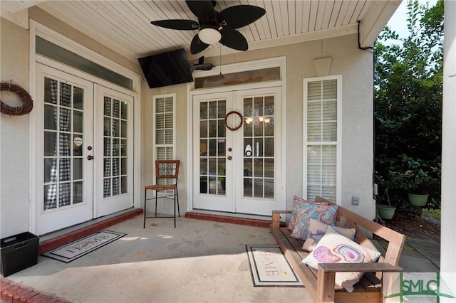 view of exterior entry with stucco siding, french doors, and a ceiling fan