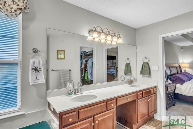 ensuite bathroom featuring healthy amount of natural light, double vanity, and a textured ceiling