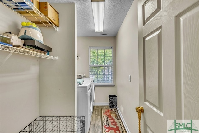 washroom featuring washing machine and clothes dryer, wood finished floors, and a textured ceiling
