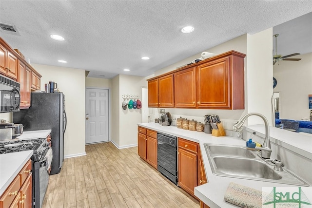 kitchen with black appliances, a sink, light countertops, light wood-style flooring, and a textured ceiling