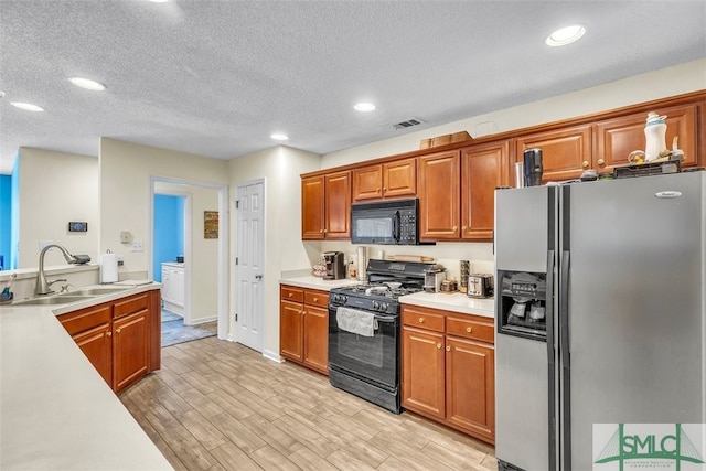 kitchen featuring black appliances, a sink, light countertops, light wood-type flooring, and recessed lighting