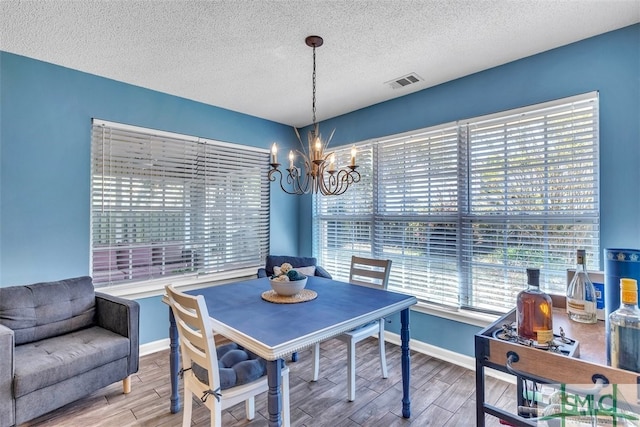 dining area featuring a chandelier, wood finish floors, a textured ceiling, and baseboards