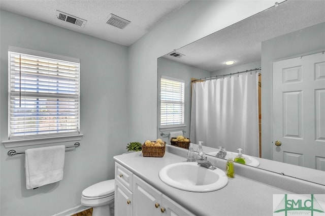 full bath with a textured ceiling, toilet, vanity, and curtained shower