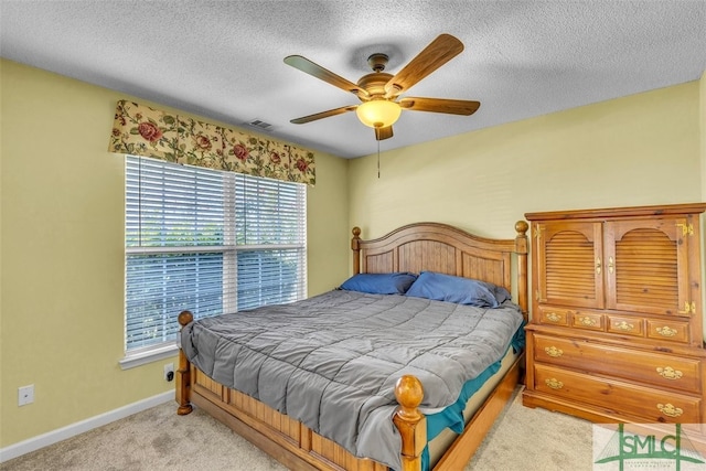 bedroom featuring light colored carpet, baseboards, a textured ceiling, and ceiling fan