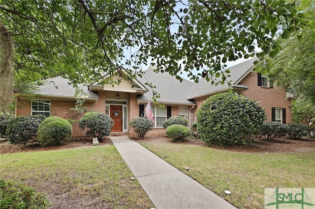 view of front of house with brick siding, a front lawn, and roof with shingles