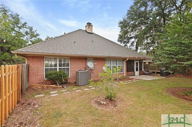 back of property with a chimney, cooling unit, a shingled roof, and brick siding