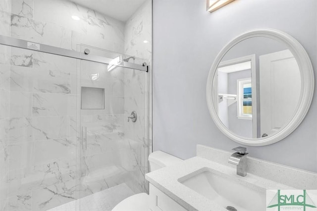 bathroom featuring a marble finish shower, toilet, and vanity