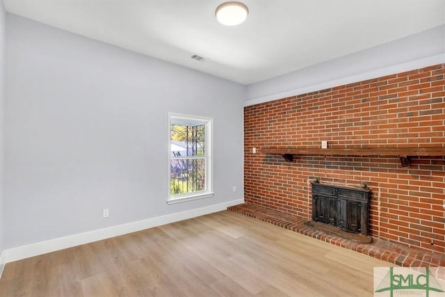 unfurnished living room with baseboards, a fireplace, visible vents, and wood finished floors