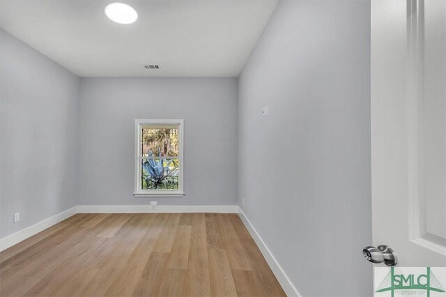 empty room featuring light wood-style floors, baseboards, and visible vents