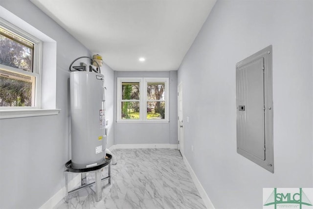interior space with a wealth of natural light, electric water heater, baseboards, and electric panel