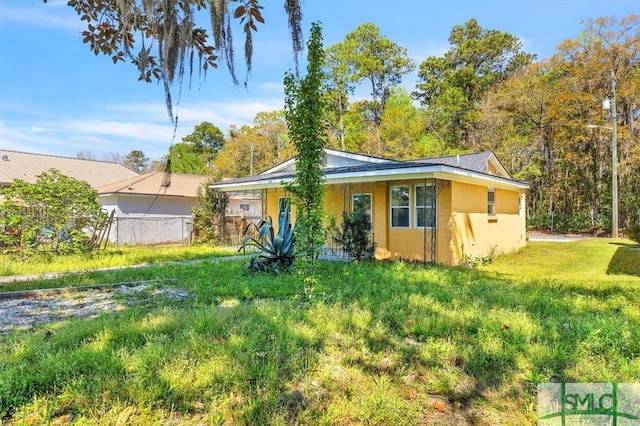 view of front of property featuring stucco siding, fence, and a front yard