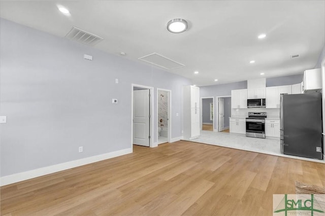 unfurnished living room featuring recessed lighting, attic access, light wood finished floors, and visible vents