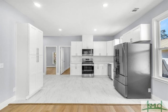kitchen featuring light countertops, visible vents, light wood finished floors, stainless steel appliances, and white cabinetry
