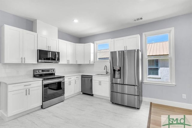 kitchen featuring white cabinetry, light countertops, stainless steel appliances, a sink, and visible vents