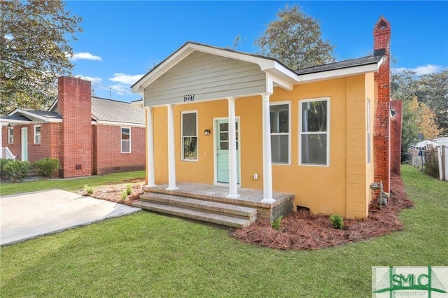 view of front facade with a front lawn, a chimney, and stucco siding