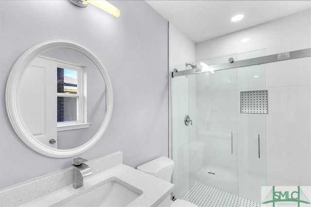 bathroom with toilet, vanity, a stall shower, and recessed lighting