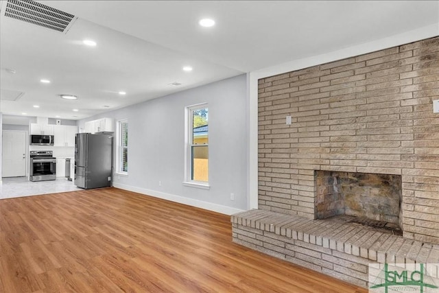 unfurnished living room with recessed lighting, baseboards, light wood-style floors, visible vents, and a brick fireplace