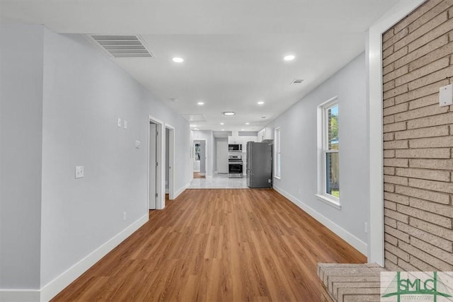 unfurnished living room featuring recessed lighting, baseboards, light wood finished floors, and visible vents
