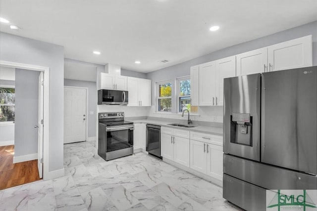 kitchen with marble finish floor, white cabinets, a sink, and stainless steel appliances