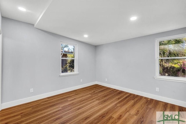 unfurnished room featuring plenty of natural light, baseboards, wood finished floors, and recessed lighting