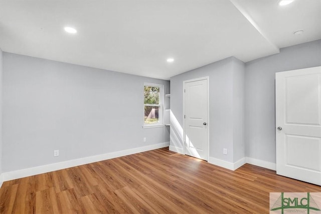 spare room with baseboards, wood finished floors, and recessed lighting