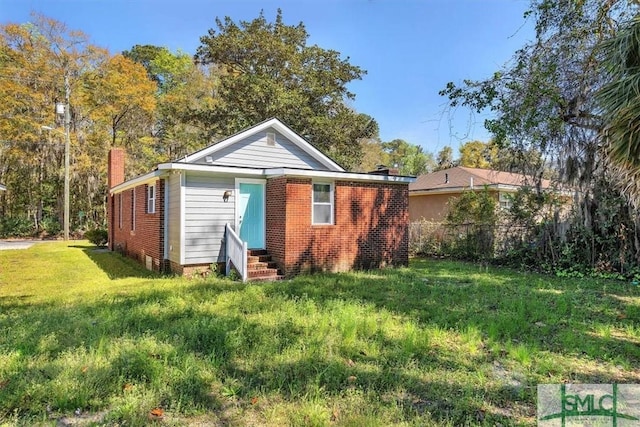back of house featuring brick siding, fence, a yard, and entry steps