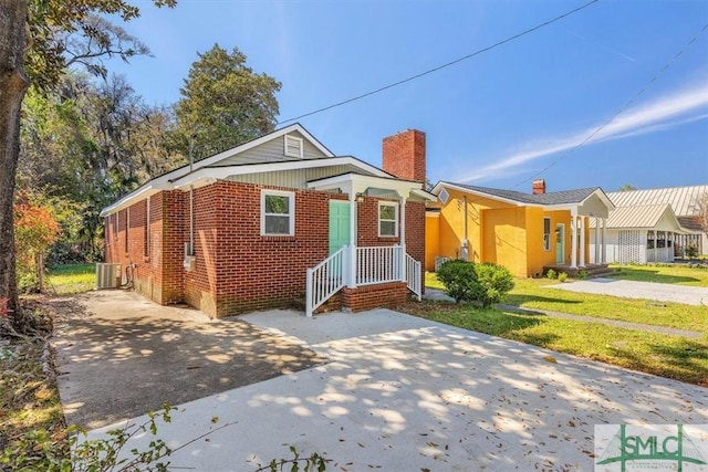 bungalow-style home with a chimney, a front lawn, and brick siding