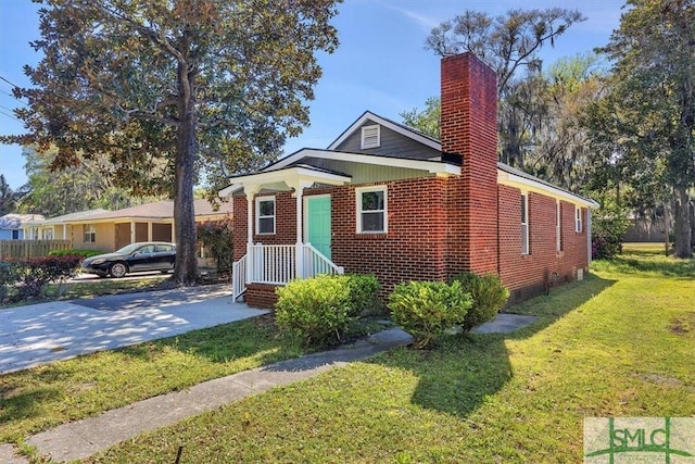 bungalow-style home with brick siding, a front yard, and a chimney
