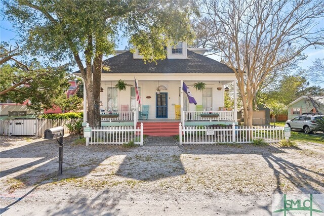 bungalow featuring a shingled roof, a fenced front yard, and a porch