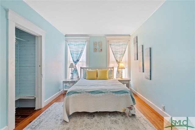 bedroom featuring baseboards, ornamental molding, and wood finished floors