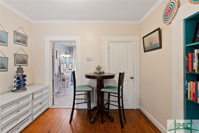 dining space with baseboards, ornamental molding, and wood-type flooring