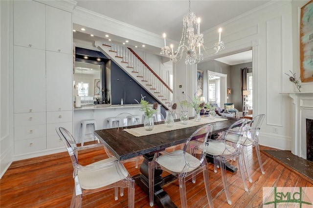 909 Howard St, Savannah, GA 31401 - dining area with stairs, crown molding, hardwood / wood-style flooring, a decorative wall, and an inviting chandelier