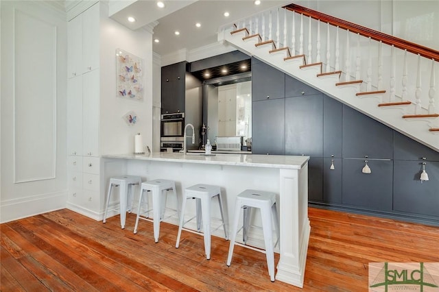 909 Howard St, Savannah, GA 31401 - kitchen featuring recessed lighting, light wood-type flooring, a breakfast bar, a sink, and a peninsula