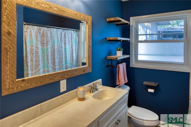 bathroom featuring toilet, vanity, and a shower with curtain