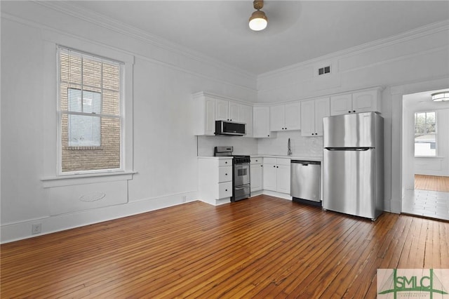 306 E Victory Dr, Savannah, GA 31405 - kitchen featuring dark wood finished floors, visible vents, appliances with stainless steel finishes, and white cabinetry