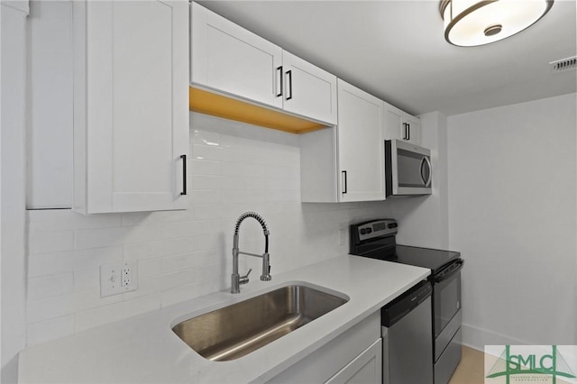 306 E Victory Dr, Savannah, GA 31405 - kitchen with tasteful backsplash, a sink, white cabinetry, light countertops, and appliances with stainless steel finishes