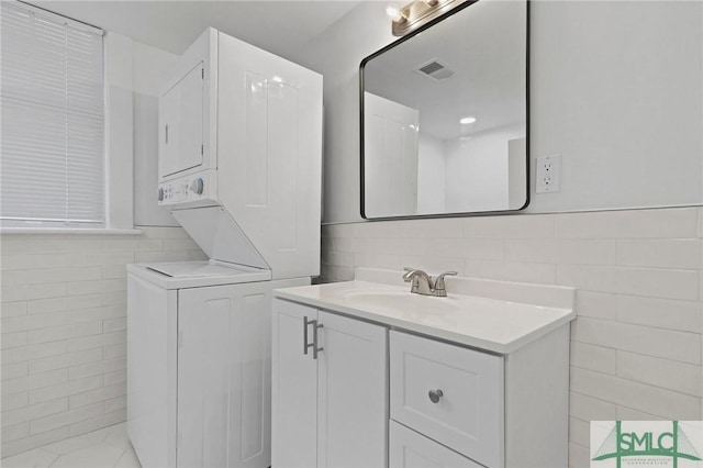 306 E Victory Dr, Savannah, GA 31405 - bathroom with tile walls, visible vents, stacked washing maching and dryer, and vanity