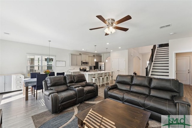 148 Spring Hill Dr, Richmond Hill, GA 31324 - living area with stairway, wood finished floors, visible vents, arched walkways, and ceiling fan