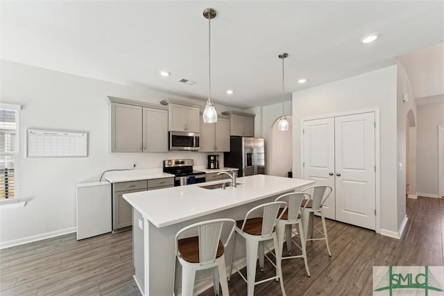 148 Spring Hill Dr, Richmond Hill, GA 31324 - kitchen with a breakfast bar area, gray cabinets, stainless steel appliances, a center island with sink, and a sink