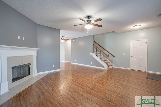 402 Walthour Dr, Rincon, GA 31326 - unfurnished living room with a ceiling fan, stairway, hardwood / wood-style floors, a fireplace, and a textured ceiling