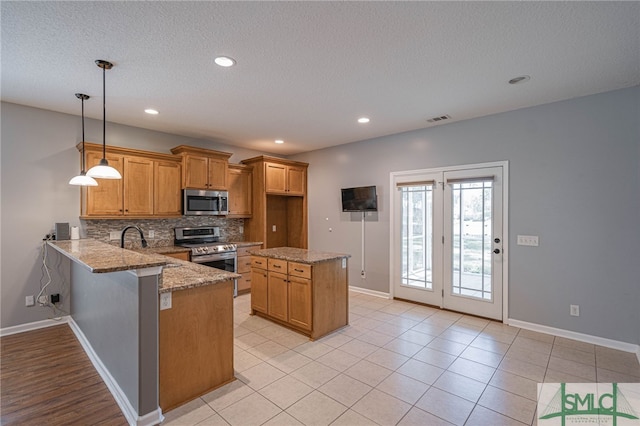402 Walthour Dr, Rincon, GA 31326 - kitchen featuring appliances with stainless steel finishes, brown cabinets, decorative backsplash, baseboards, and light stone countertops