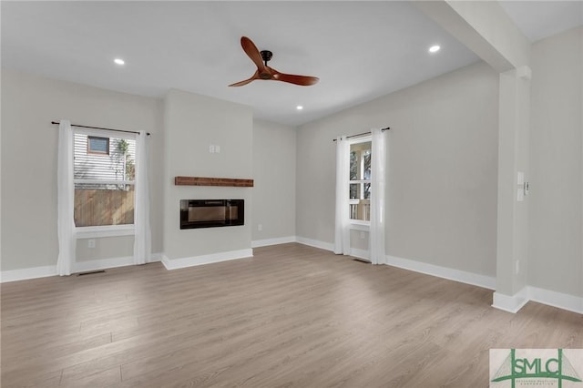 unfurnished living room featuring recessed lighting, wood finished floors, ceiling fan, and a glass covered fireplace