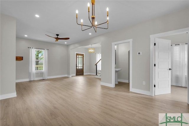 unfurnished living room with baseboards, light wood-style flooring, and ceiling fan with notable chandelier