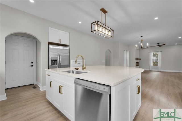 kitchen with a sink, stainless steel appliances, decorative light fixtures, and arched walkways