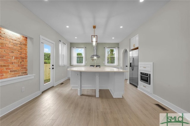 kitchen featuring light countertops, stainless steel appliances, light wood-style flooring, and visible vents