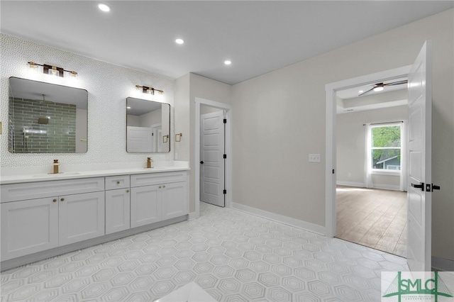 full bath featuring baseboards, recessed lighting, double vanity, and a sink
