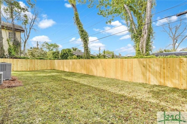 view of yard featuring a fenced backyard and central AC