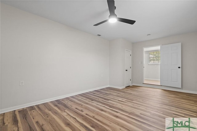 unfurnished room with baseboards, visible vents, wood finished floors, and ceiling fan
