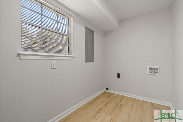washroom with electric panel, hookup for a washing machine, baseboards, wood finished floors, and laundry area