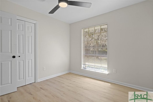 unfurnished bedroom featuring baseboards, a closet, wood finished floors, and ceiling fan
